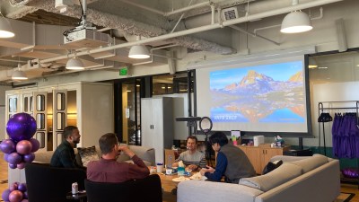 Dialpad employees at the WeWork office in San Francisco sit around a large coffee table in a lounge space.